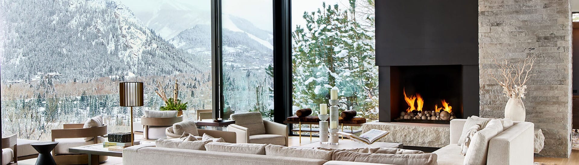 Reynaers Aluminum lift and slide doors with fireplace and snowy mountains visible through glass and massive door opening