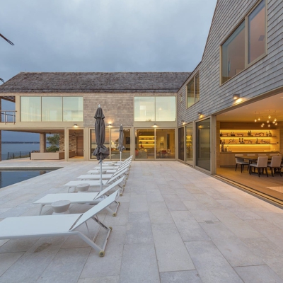 Massive wood lift and slide doors open to patio on the water