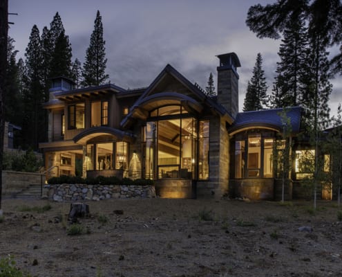 Exterior night view of modern mountain home with tall wood windows