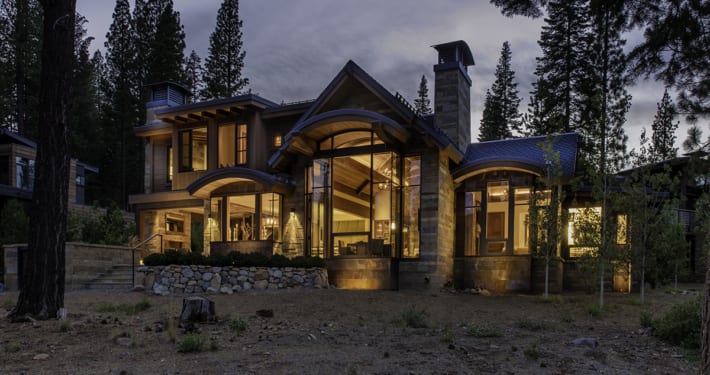 Exterior night view of modern mountain home with tall wood windows