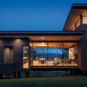 Exterior night view of lighted modern home with residential window walls