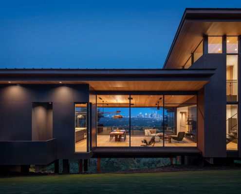 Exterior night view of lighted modern home with residential window walls